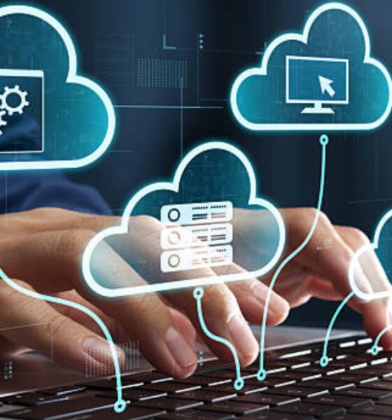 Illustration of cloud computing services with interconnected cloud icons, servers, software, and computer systems displayed above a person typing on a laptop keyboard.