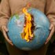 Burning globe held in hands symbolizing global warming and climate crisis