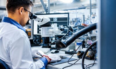 A scientist using a microscope and advanced laboratory equipment during nanophotonics research on the optical properties of metals.