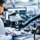 A scientist using a microscope and advanced laboratory equipment during nanophotonics research on the optical properties of metals.