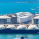 LNG import terminal with large liquefied natural gas storage tanks and an LNG carrier docked at a coastal port.