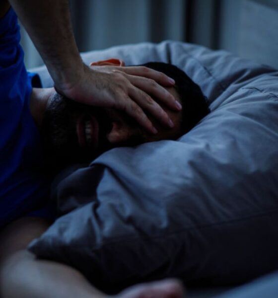 A person lying awake in bed on a warm night, illustrating sleep loss linked to rising nighttime temperatures.