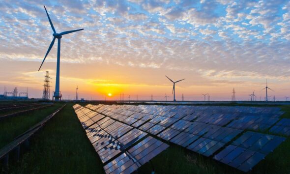 Solar panels and wind turbines generating renewable energy at sunset, representing India's growing solar and wind power capacity.