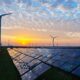 Solar panels and wind turbines generating renewable energy at sunset, representing India's growing solar and wind power capacity.
