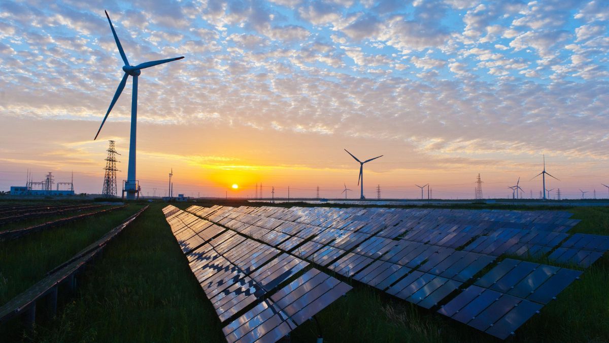 Solar panels and wind turbines generating renewable energy at sunset, representing India's growing solar and wind power capacity.