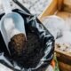 Alt text: Nitrogen fertiliser in a scoop over soil and organic compost