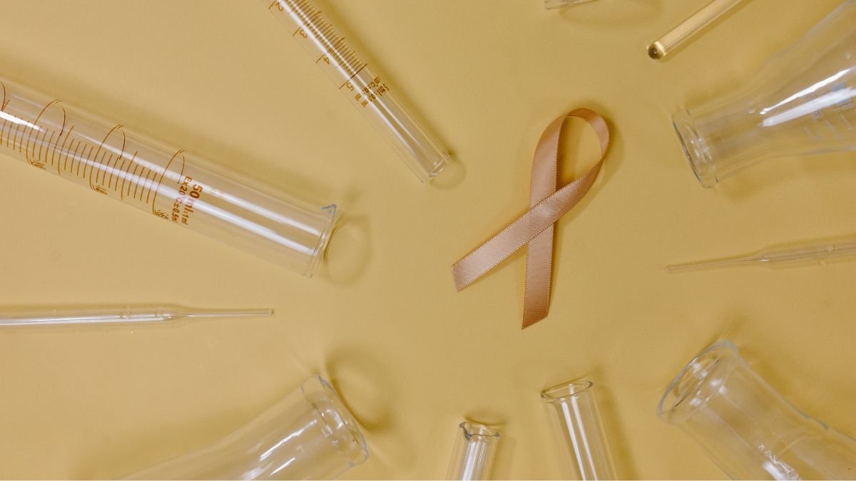 Cancer research laboratory setup with test tubes, syringes and a pink cancer awareness ribbon