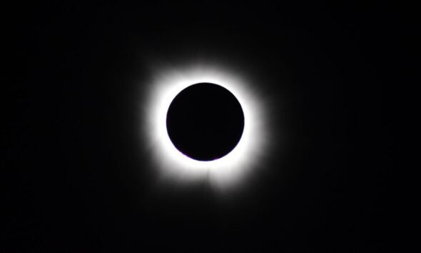 Total solar eclipse with the Moon completely covering the Sun, revealing the glowing solar corona