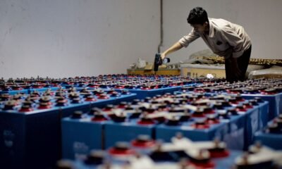 Worker assembling a large array of batteries at an energy storage facility.
