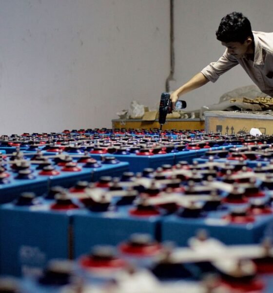 Worker assembling a large array of batteries at an energy storage facility.