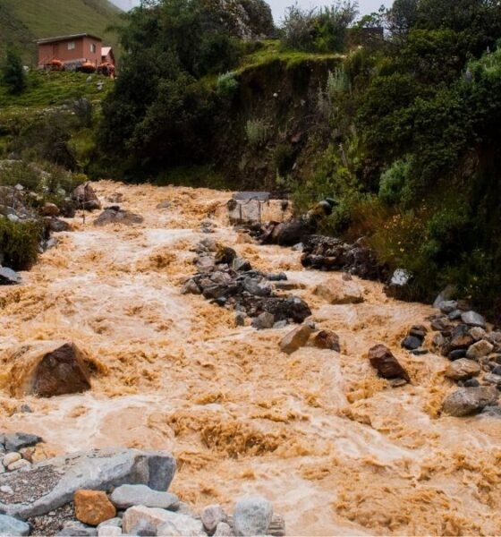 Muddy floodwater rushing through a rocky Himalayan stream near a mountain settlement in Nepal