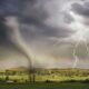 Tornado and lightning over a rural landscape, illustrating the threat of unprecedented extreme events.