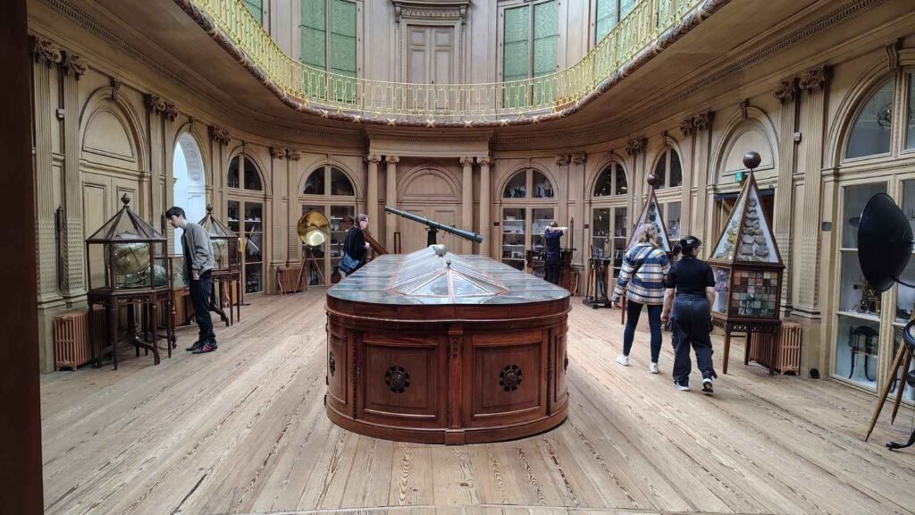 Historic Oval Room at Teylers Museum with scientific instruments and wooden display cases