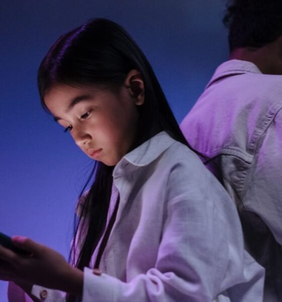 Two teenagers using smartphones in a dimly lit room, highlighting concerns around social media use and child online safety.