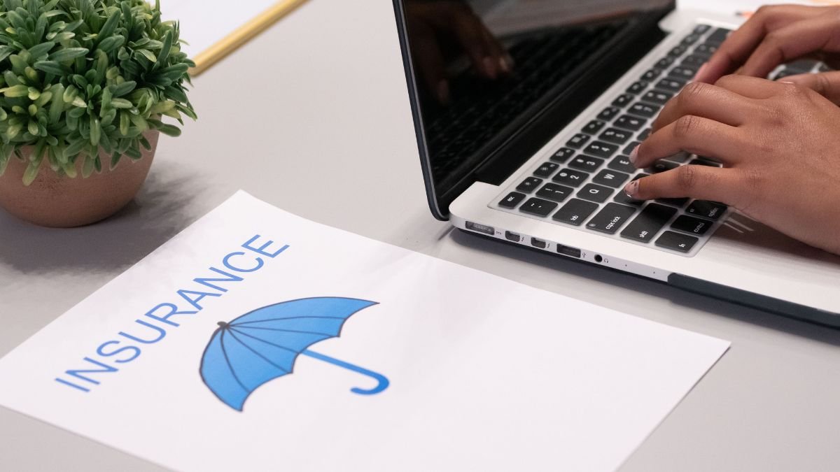 Insurance document with umbrella graphic beside a laptop, illustrating disaster insurance and financial protection against losses.