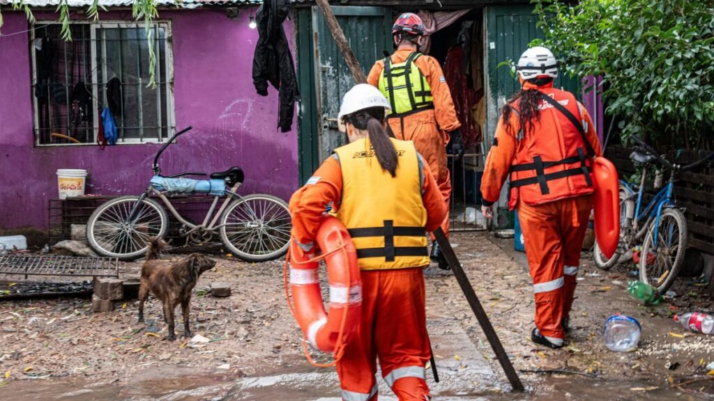 Disaster response workers in protective gear inspect a flooded residential area, illustrating the financial challenges of disaster recovery in India.