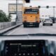 Cars and a city bus travel through busy urban traffic, illustrating connected and autonomous vehicle technology.