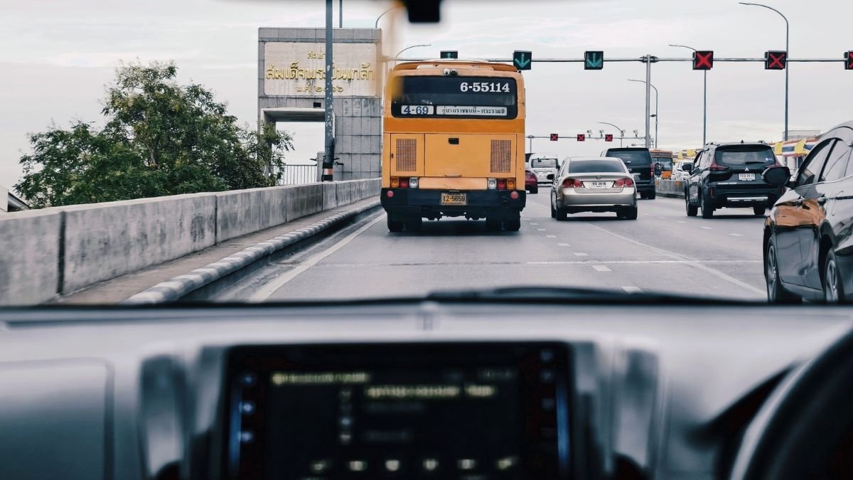 Cars and a city bus travel through busy urban traffic, illustrating connected and autonomous vehicle technology.