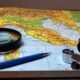 Map with a compass, magnifying glass and navigation tools, illustrating the representation of geographical size on world maps.