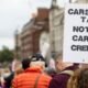 Protester holds a “Carbon Tax Not Carbon Credits” sign as carbon pricing gains importance in global trade
