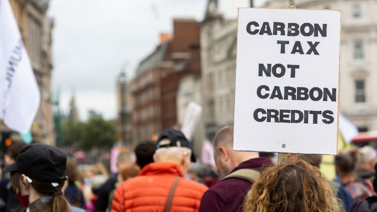 Protester holds a “Carbon Tax Not Carbon Credits” sign as carbon pricing gains importance in global trade
