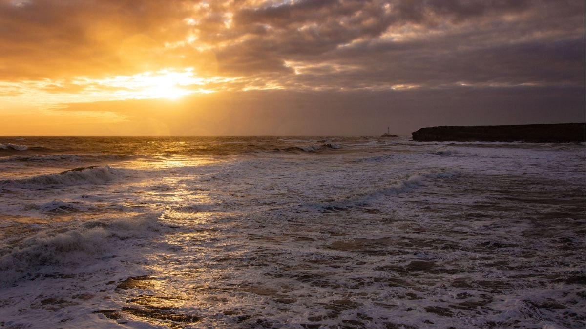 Ocean waves under a dramatic sunset as global ocean temperatures reach record highs