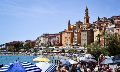 Mediterranean coastal city with a densely built hillside and crowded beach during hot summer weather, illustrating heat exposure in European cities.