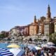 Mediterranean coastal city with a densely built hillside and crowded beach during hot summer weather, illustrating heat exposure in European cities.