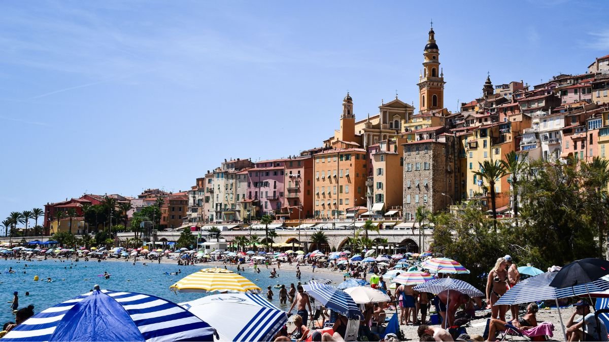 Mediterranean coastal city with a densely built hillside and crowded beach during hot summer weather, illustrating heat exposure in European cities.