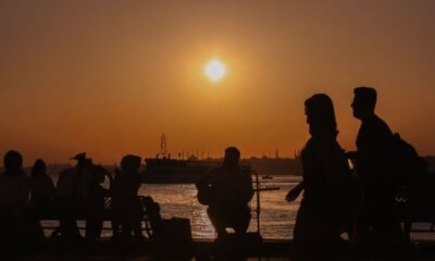 People gather by a waterfront as the sun sets during a period of rising global temperatures