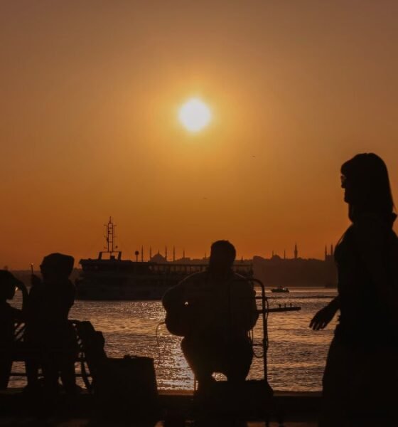 People gather by a waterfront as the sun sets during a period of rising global temperatures