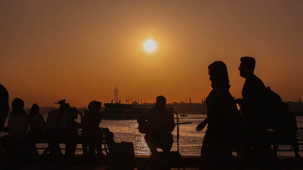 People gather by a waterfront as the sun sets during a period of rising global temperatures