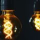 Two glowing vintage light bulbs illuminating a dark background, symbolising access to electricity.