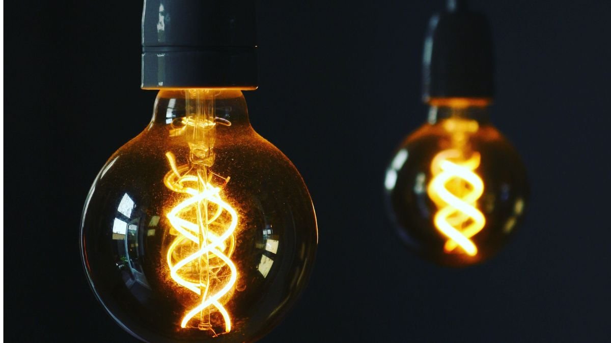 Two glowing vintage light bulbs illuminating a dark background, symbolising access to electricity.