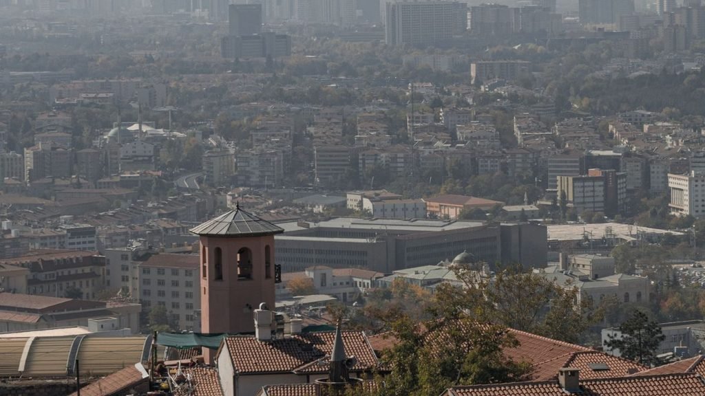 A hazy urban landscape with dense buildings and rooftops, illustrating how stagnant air can limit the dispersion during winter pollution.