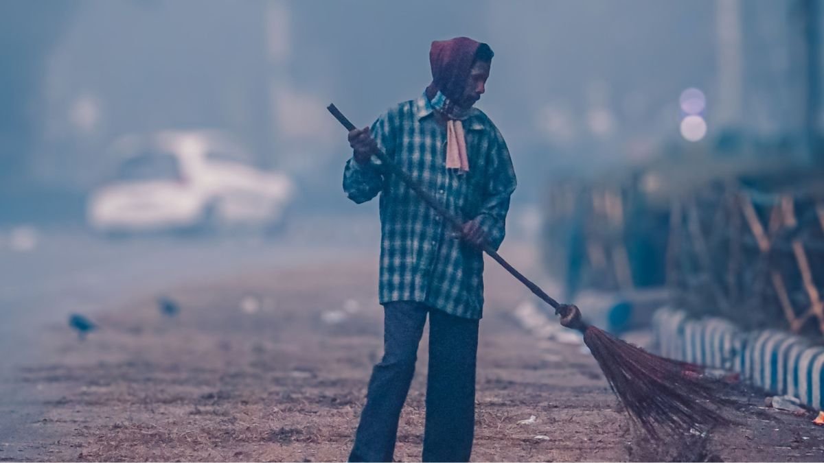 A street sweeper works along a hazy road as vehicles and the surrounding area fade into the background.