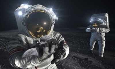 Astronaut holding a lunar rock on the Moon with another astronaut in the background, illustrating future lunar exploration.