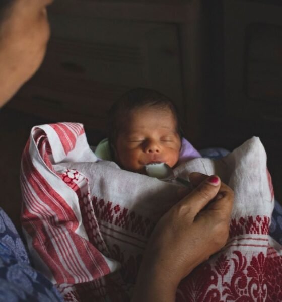 Mother feeding a newborn baby with a spoon, illustrating concerns around infant nutrition and feeding practices.