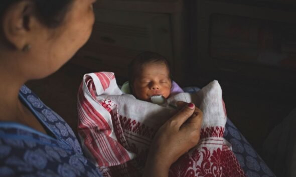 Mother feeding a newborn baby with a spoon, illustrating concerns around infant nutrition and feeding practices.