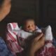 Mother feeding a newborn baby with a spoon, illustrating concerns around infant nutrition and feeding practices.