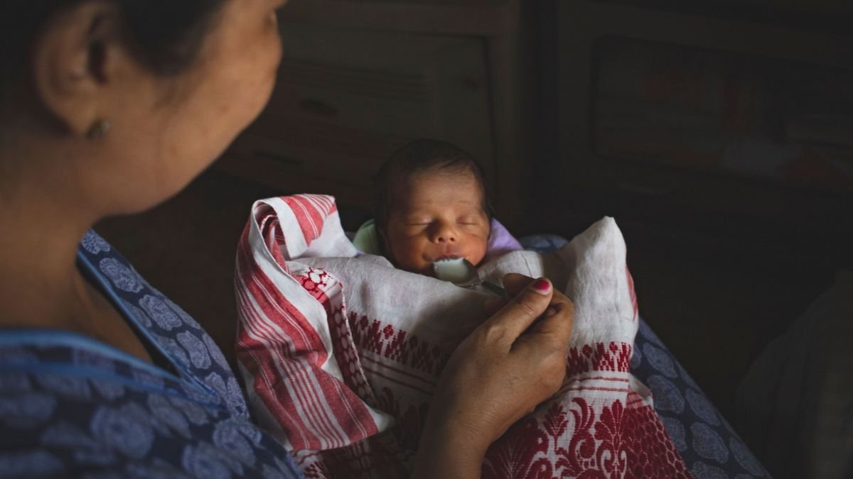 Mother feeding a newborn baby with a spoon, illustrating concerns around infant nutrition and feeding practices.