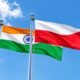 Indian and Polish national flags flying side by side against a blue sky.