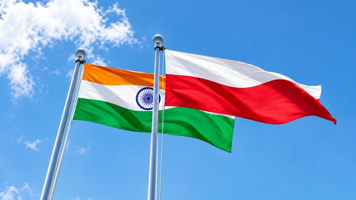 Indian and Polish national flags flying side by side against a blue sky.