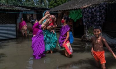 Women and children wade through floodwater around their homes, illustrating the human impact of flooding in the context of Nepal’s climate disaster recovery needs.