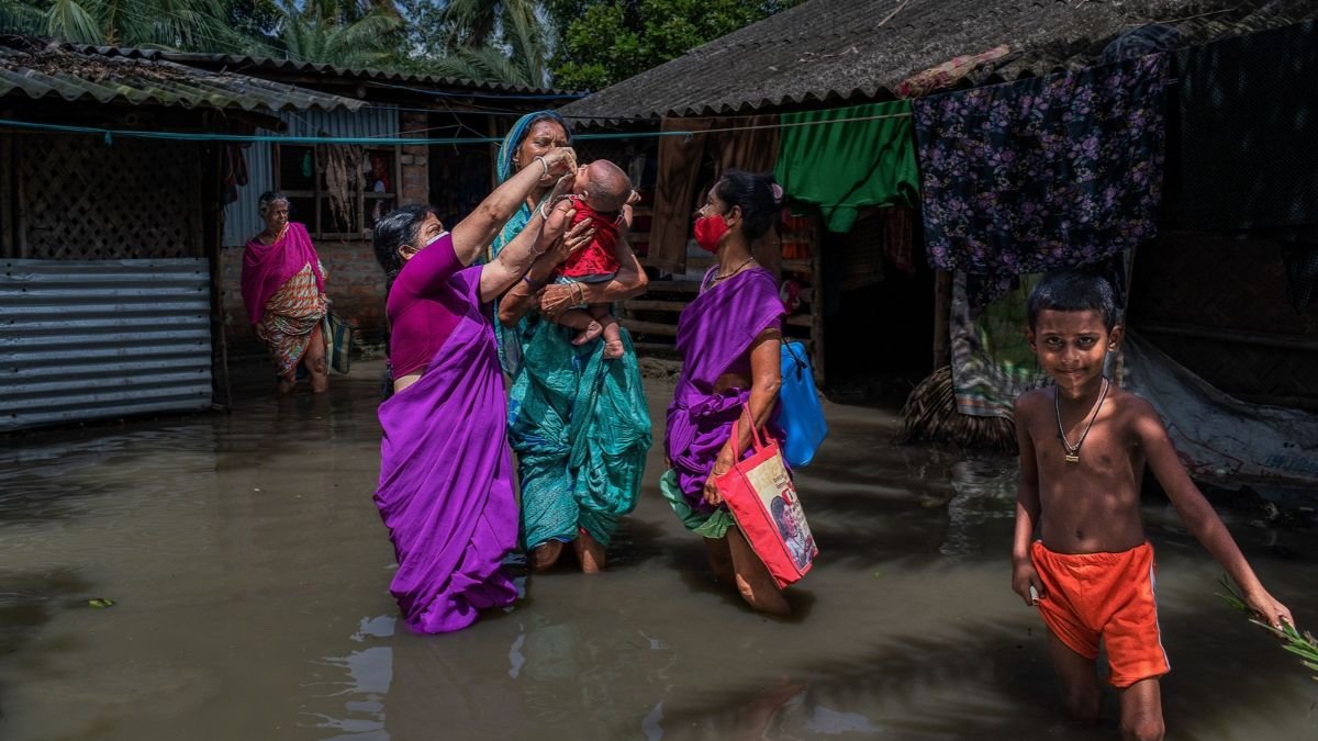 Women and children wade through floodwater around their homes, illustrating the human impact of flooding in the context of Nepal’s climate disaster recovery needs.