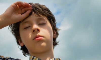 Child shielding his eyes from bright sunlight on a hot day.