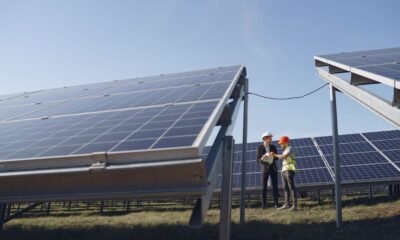 Engineers inspecting solar panels at a solar power installation under a clear blue sky.