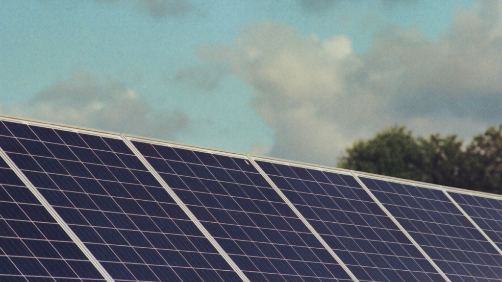 Rows of blue solar panels under a partly cloudy sky, illustrating solar energy and clean-energy technology.