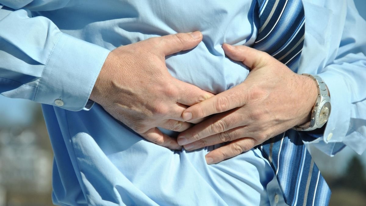 Person holding the upper abdomen, illustrating abdominal pain associated with pancreatic cancer
