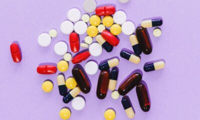 Cancer medicine price regulation in India illustrated by assorted tablets and capsules on a purple background.